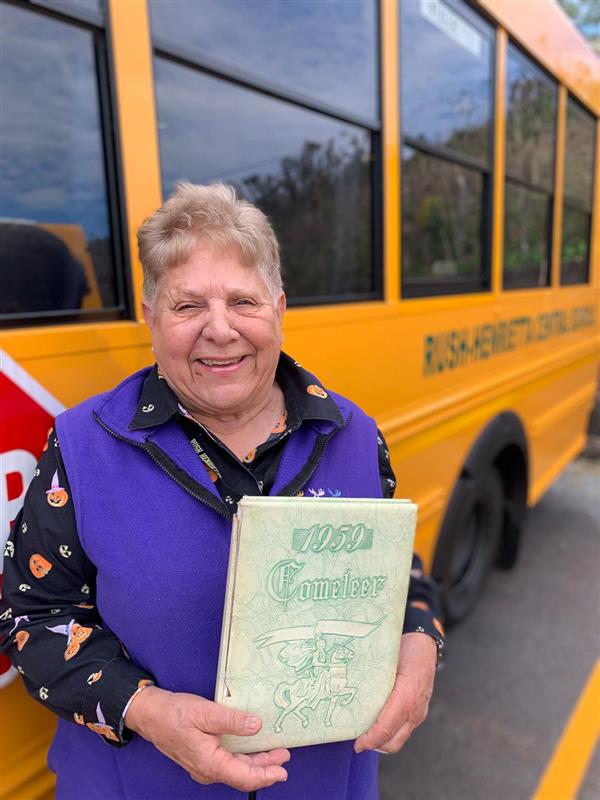 Jody Day holding her yearbook in front of her R-H bus.